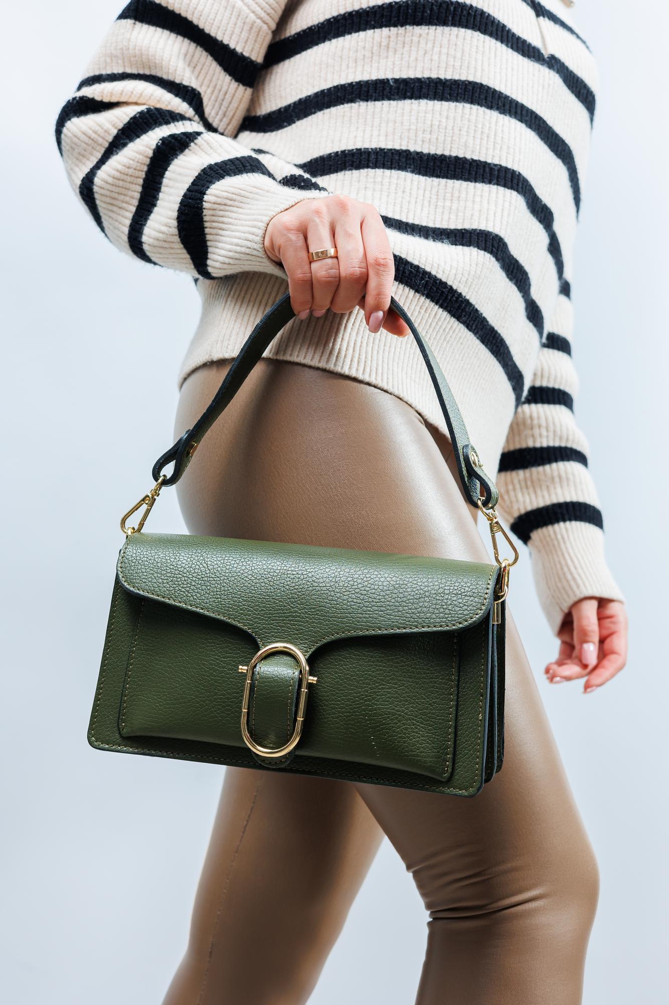 Mulher segurando uma pequena bolsa de couro verde com fecho dourado